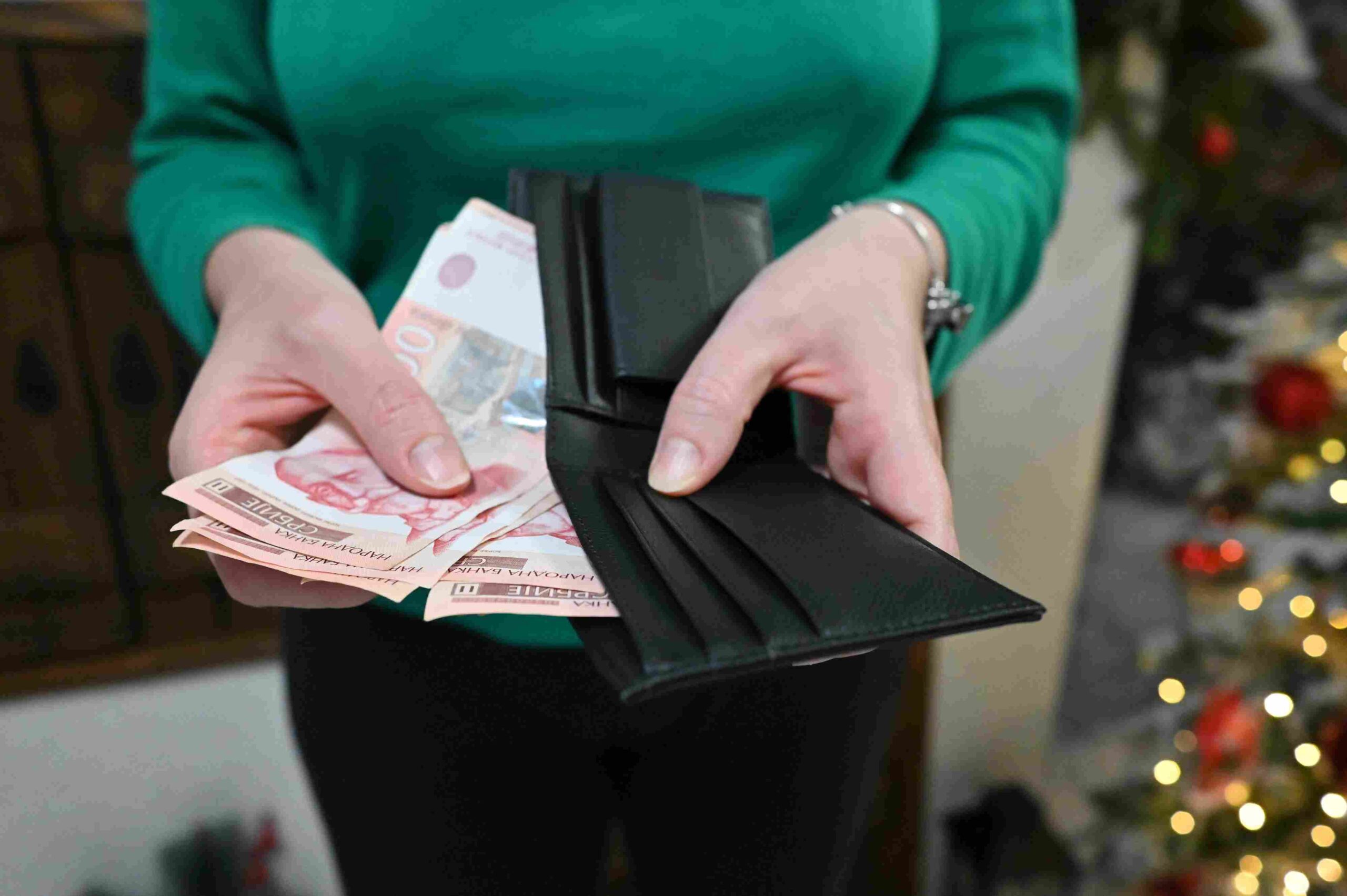 Osoba drži novčanik i novčanice dinara u rukama