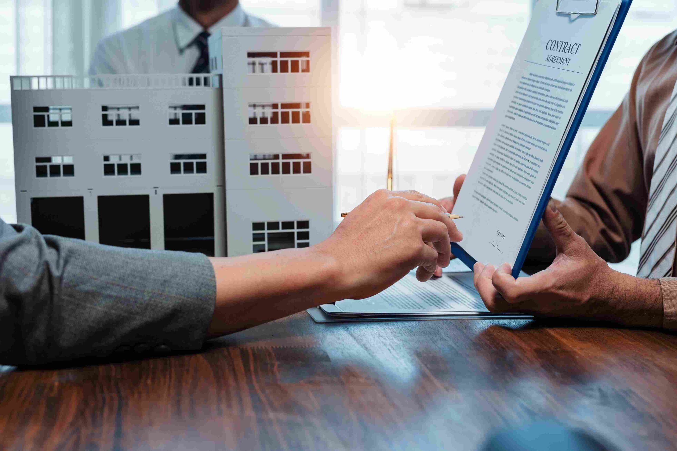 Pregled kupoprodajnog ugovora uz maketu zgrade na stolu