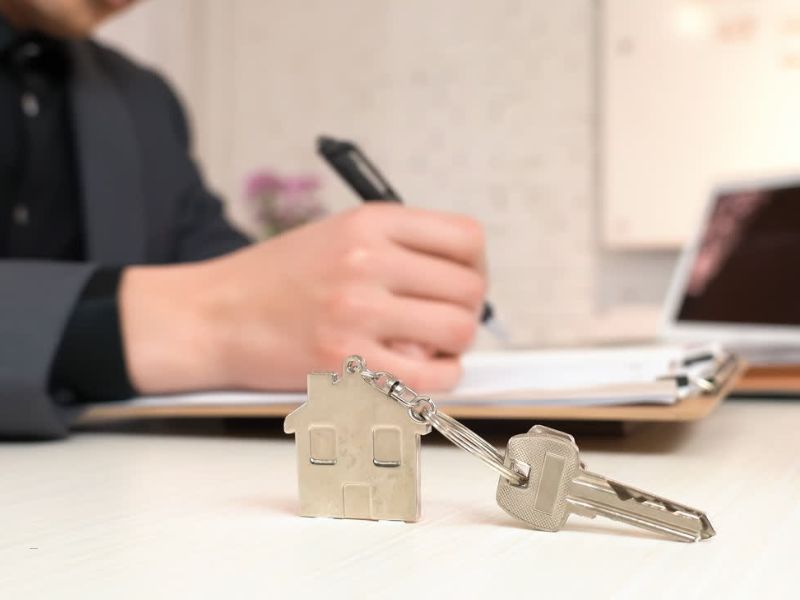 osoba potpisuje dokument za overu stana, pored ključevi od stana