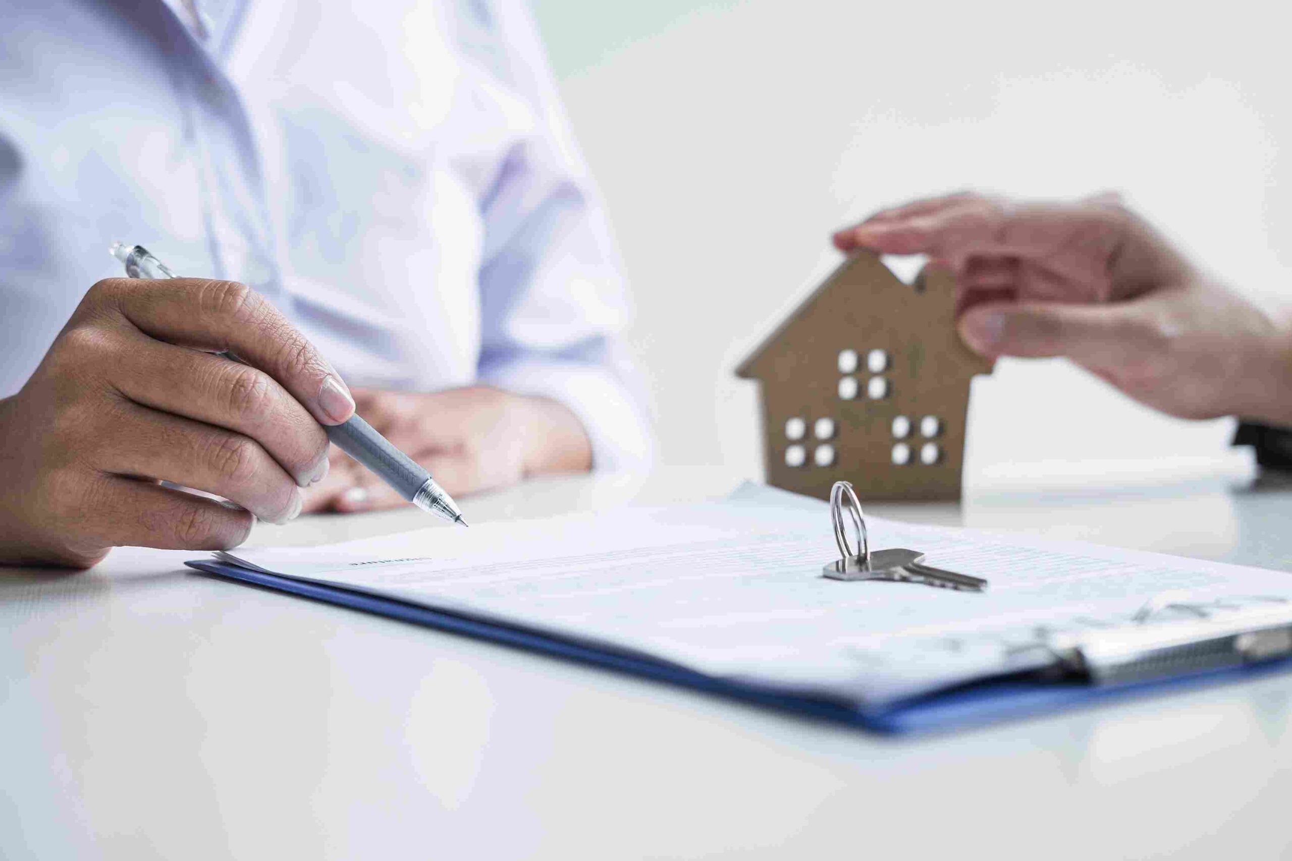 Potpisivanje ugovora o kupoprodaji uz ključeve i maketu kuće na stolu
