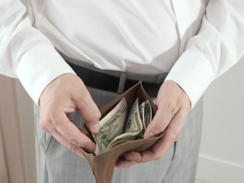 muška osoba gleda u otvoren novčanik