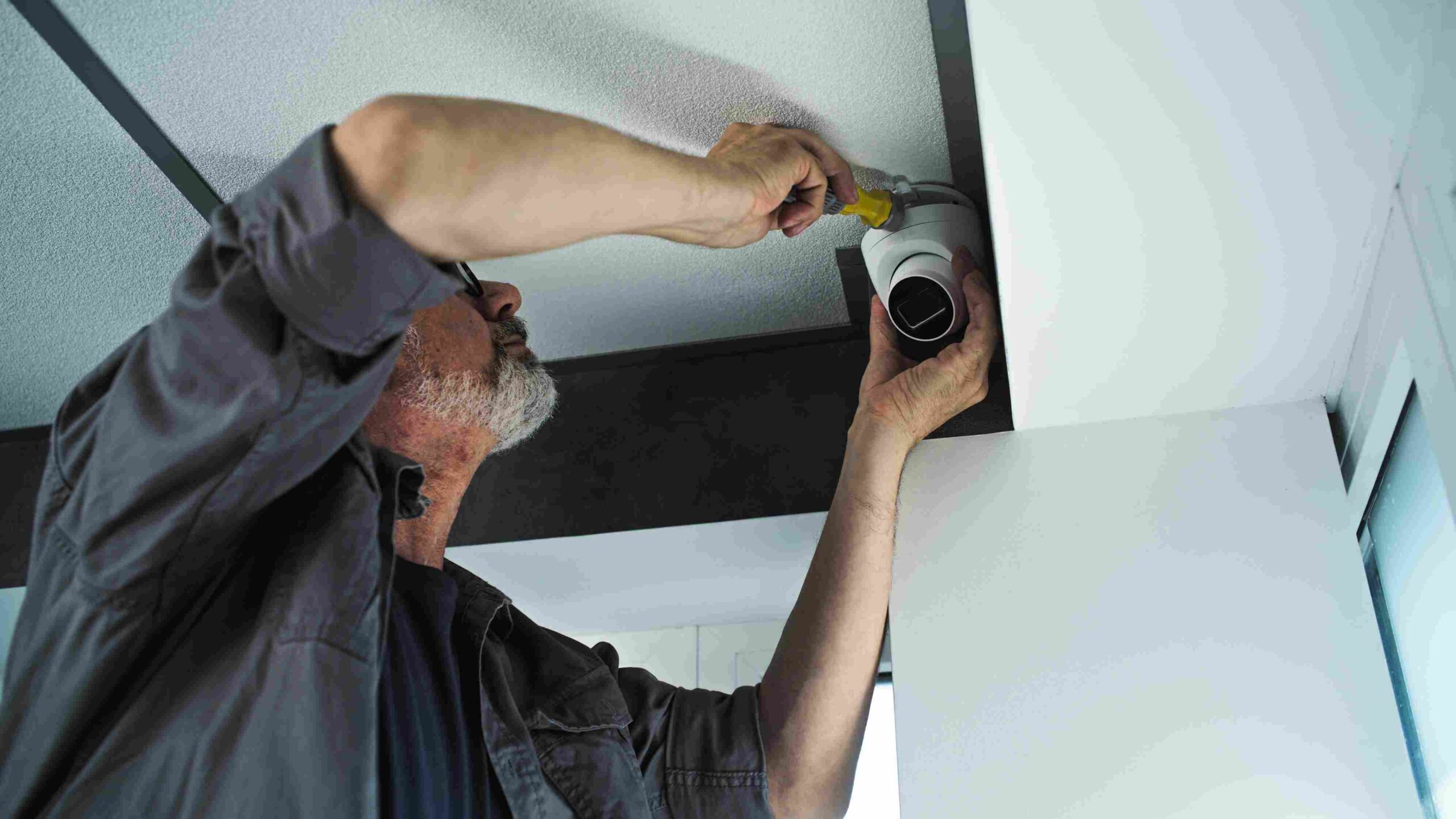 Tehničar postavlja sigurnosnu kameru na plafon poslovnog prostora