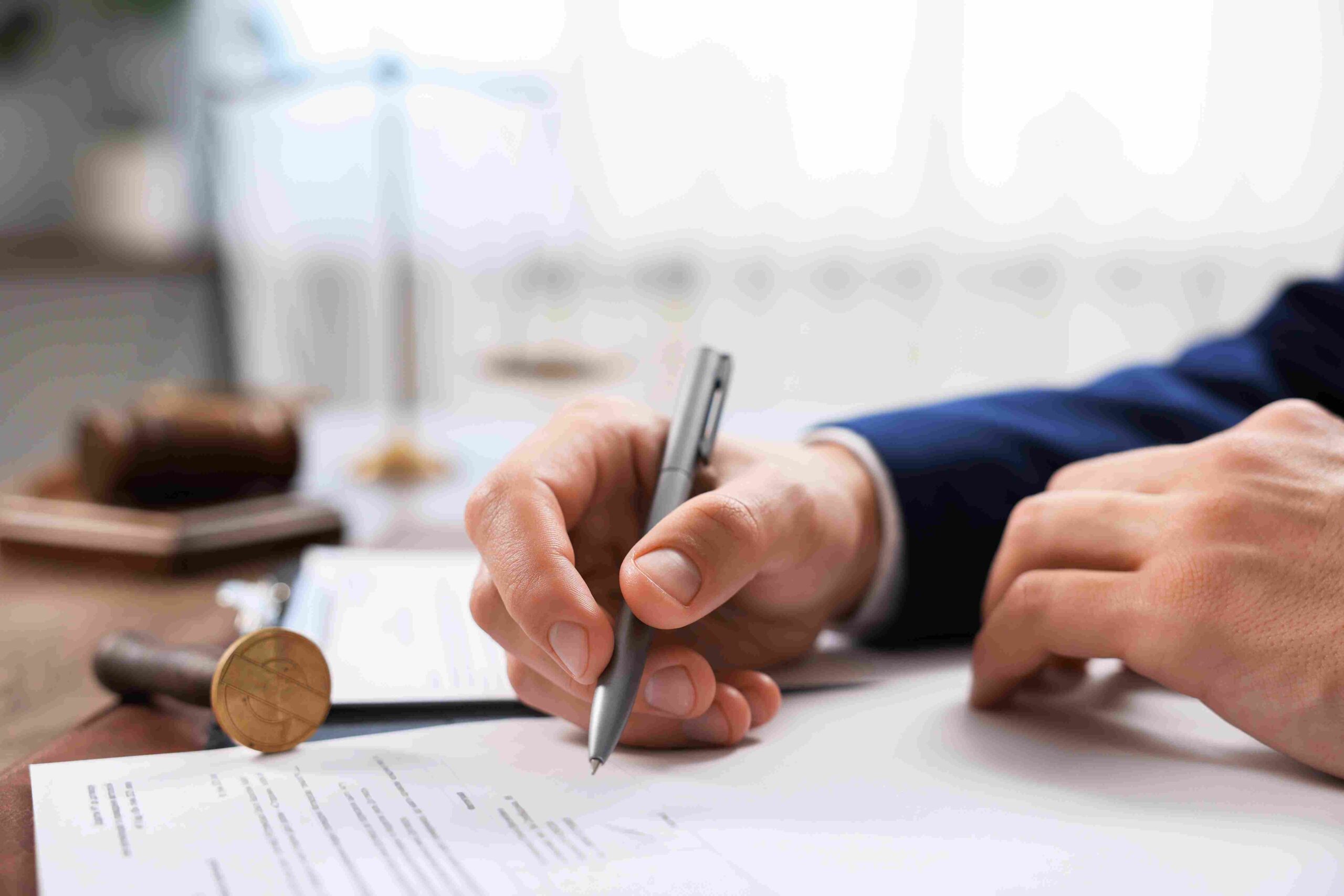 Ruka potpisuje dokument pored notarskog pečata na stolu