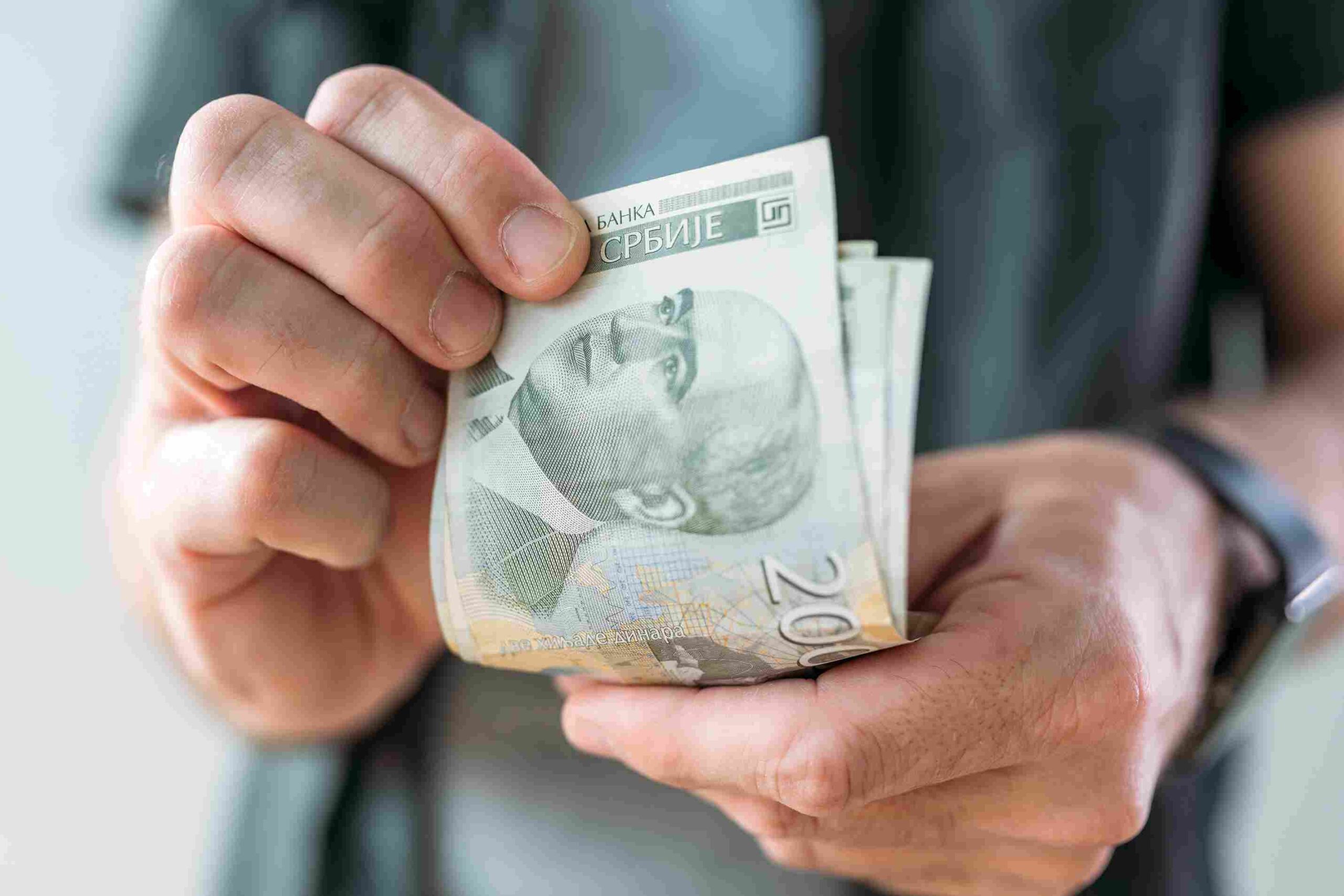 Ruke drže novčanice dinara kao simbol novčane kazne