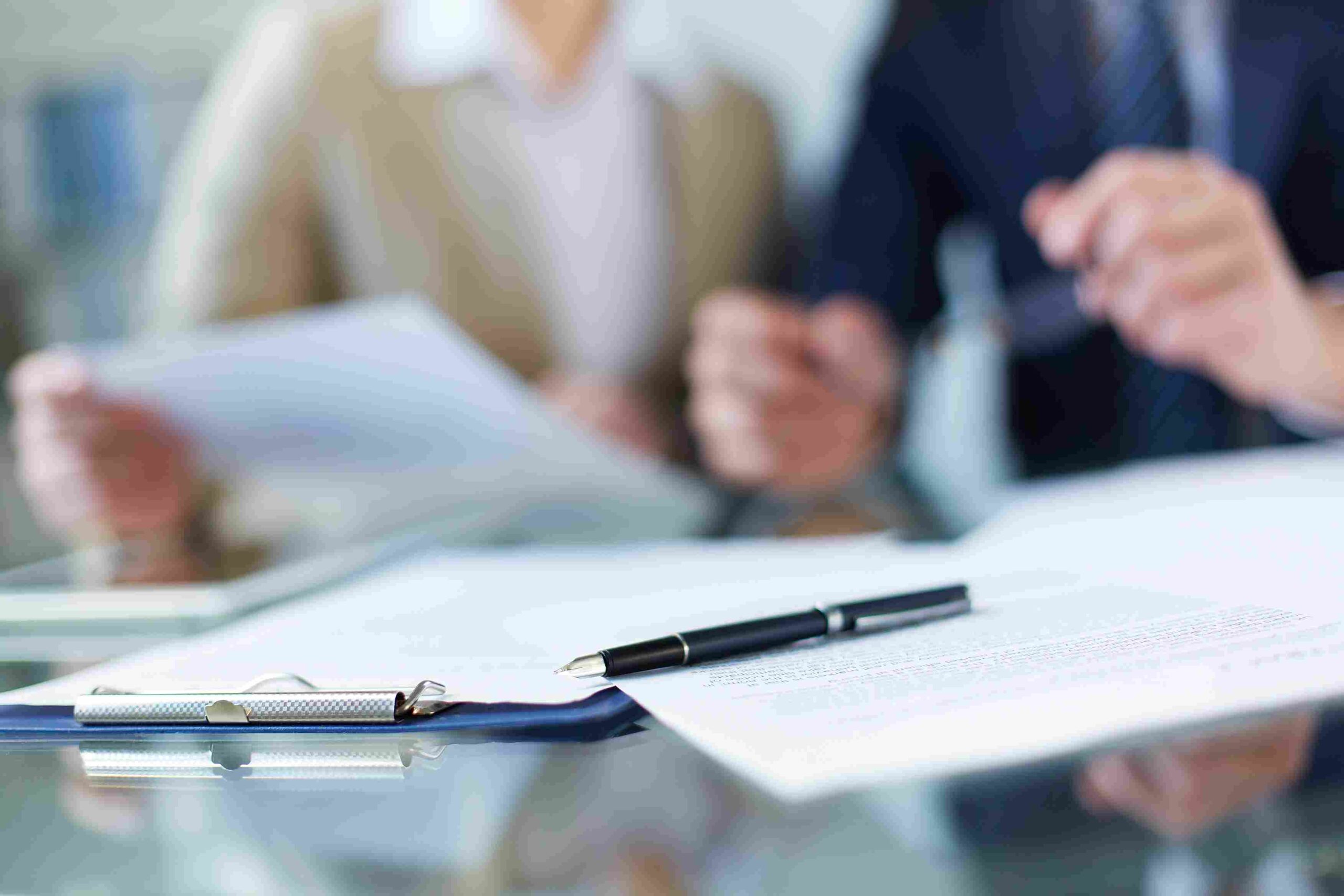 Poslovni sastanak sa dokumentima na stolu i osobama koje razgovaraju i analiziraju papire