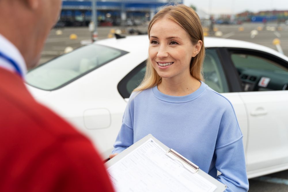 Žena pored automobila razgovara sa službenikom i drži dokumentaciju potrebnu za prenos vlasništva vozila