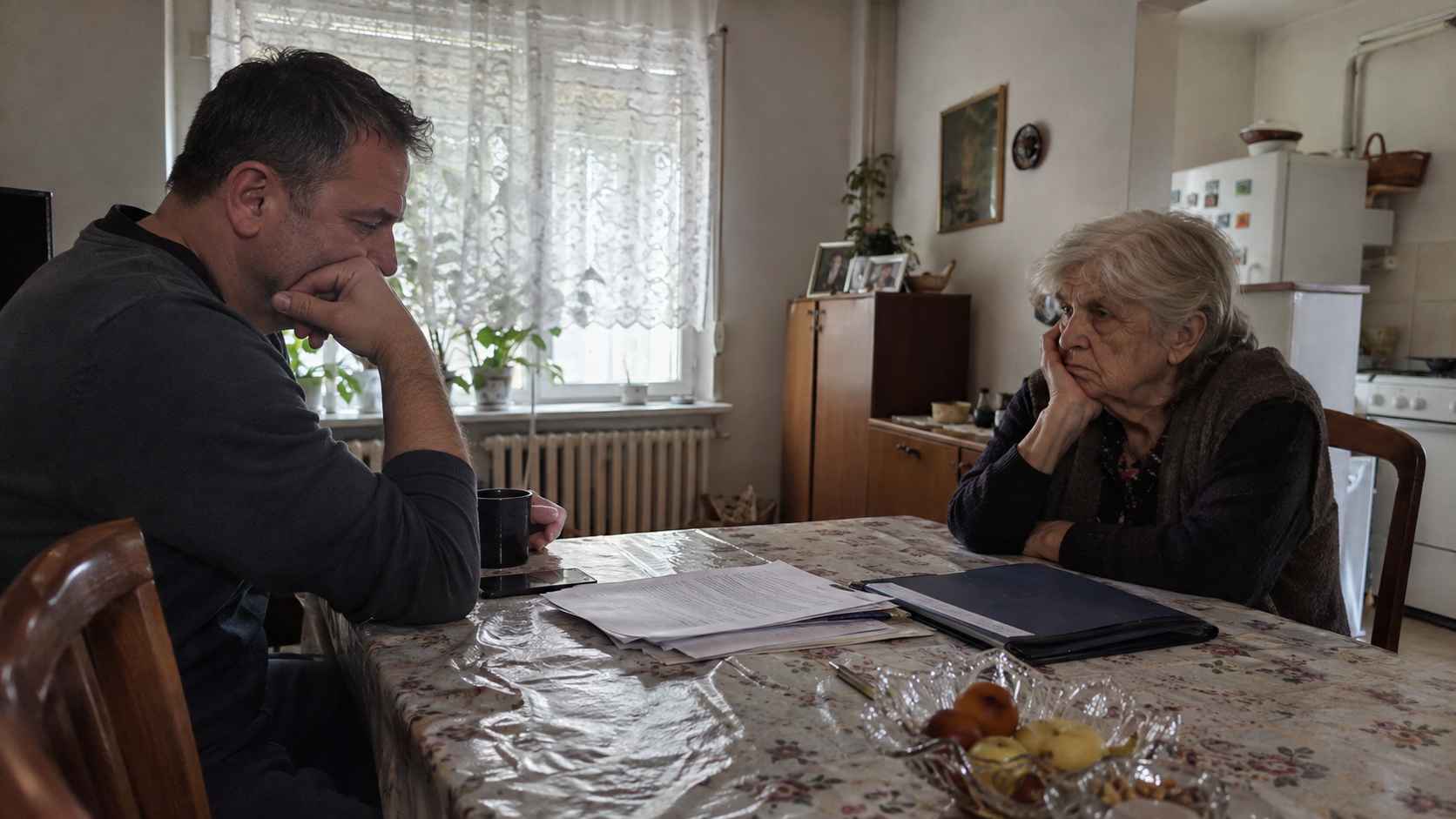 Starija žena i muškarac sede za stolom sa dokumentacijom, vidno zabrinuti zbog narušenih odnosa i mogućeg raskida ugovora o doživotnom izdržavanju.